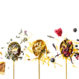 Colorful dried tea herbs on spoons against a white background