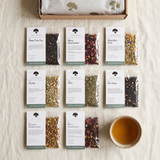 Nine organic loose leaf tea samples in labelled pouches, laid out on linen